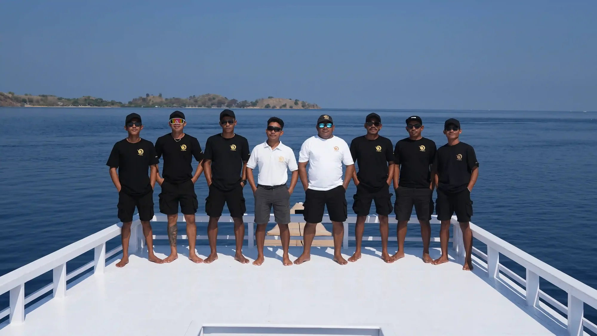 Uniformed liveaboard crew lined up on the deck of a phinisi in Labuan Bajo