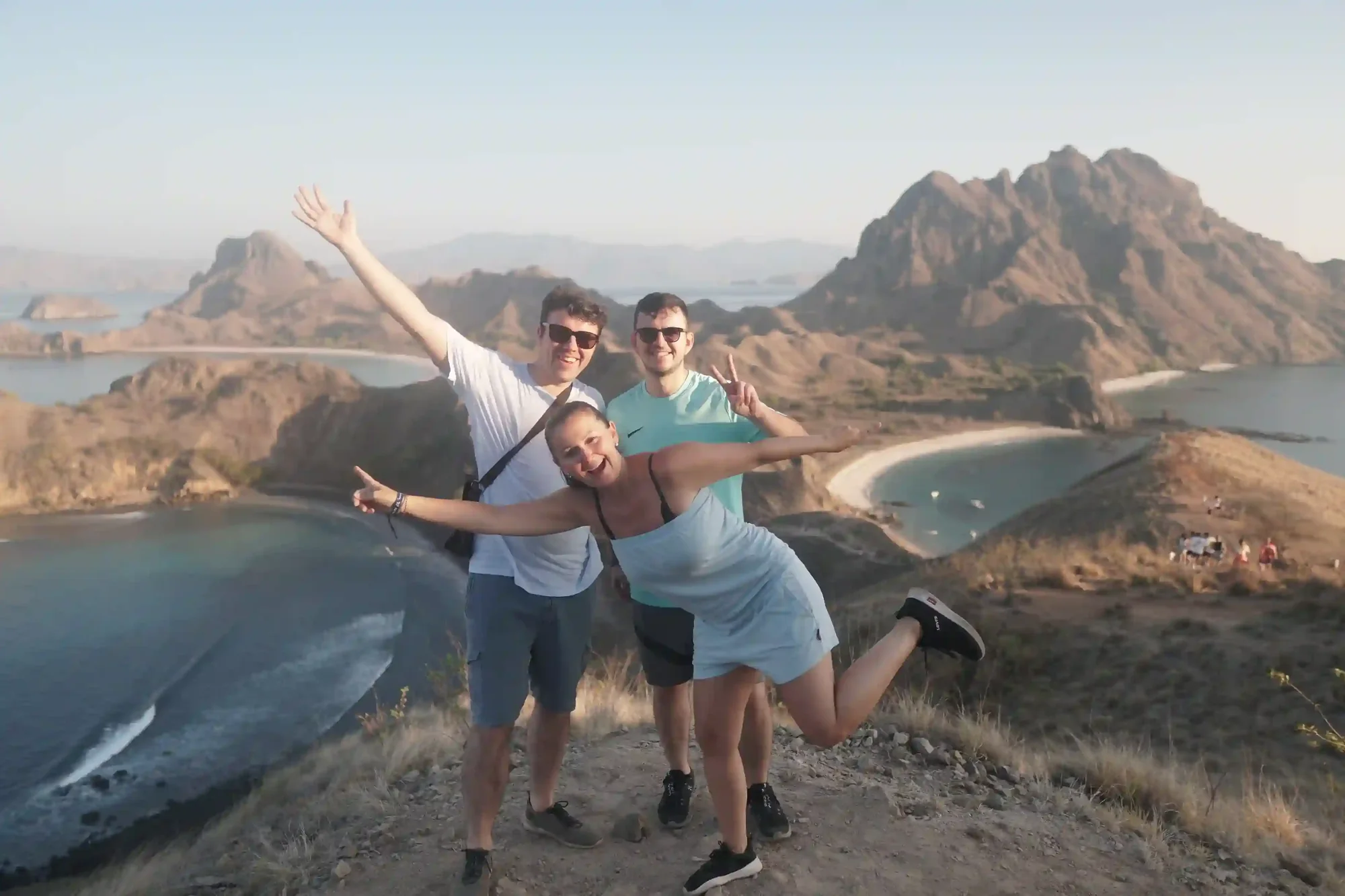 Guests standing on the Padar Island ridge above the three curved bays at sunrise
