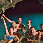 Sunlight falling through the roof of Rangko Cave onto a turquoise saltwater pool near Labuan Bajo