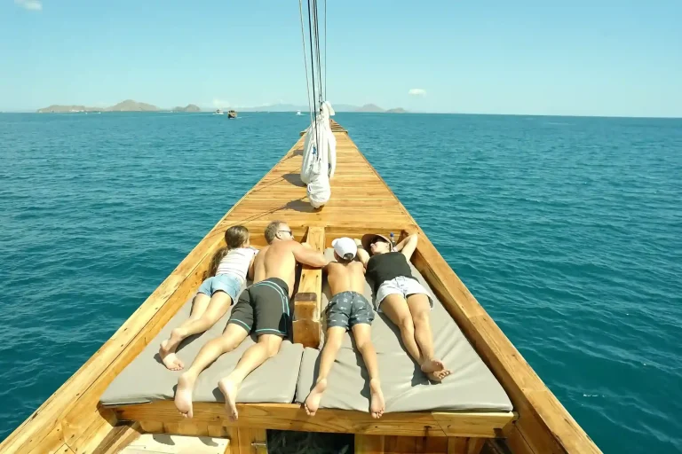 Guests and children relaxing on the open deck of a liveaboard in Komodo National Park