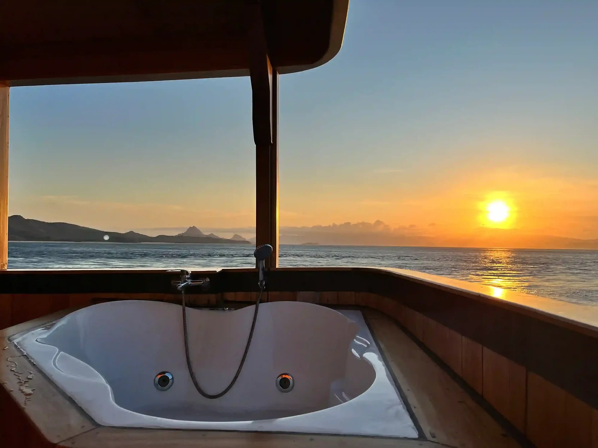 Sunset over Komodo Island seen from the deck of a luxury phinisi at anchor