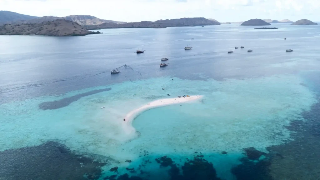 The crescent sandbar of Taka Makassar surrounded by shallow turquoise reef water