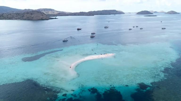 The crescent sandbar of Taka Makassar surrounded by shallow turquoise reef water