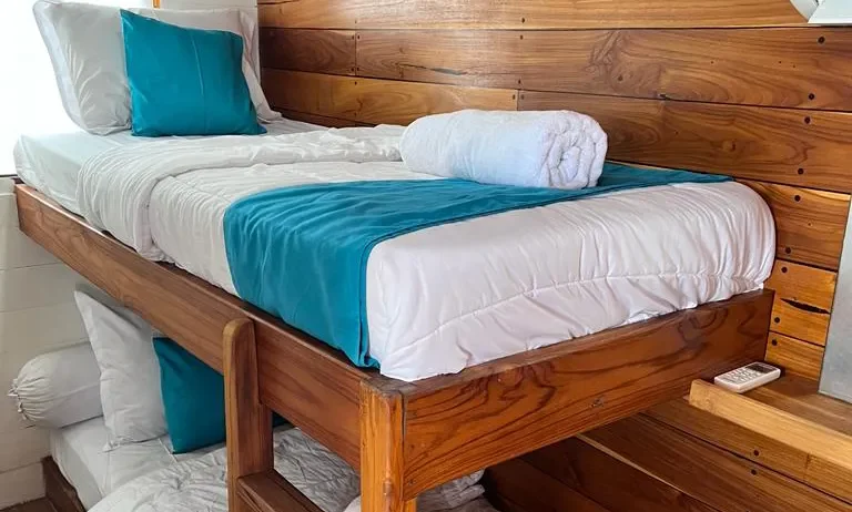 Upper bunk berth in the Superior cabin on board Lady Grace, teak panelling and folded towels